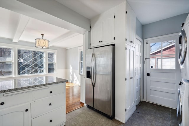 kitchen with stacked washer and dryer, stainless steel fridge with ice dispenser, white cabinetry, and stone countertops