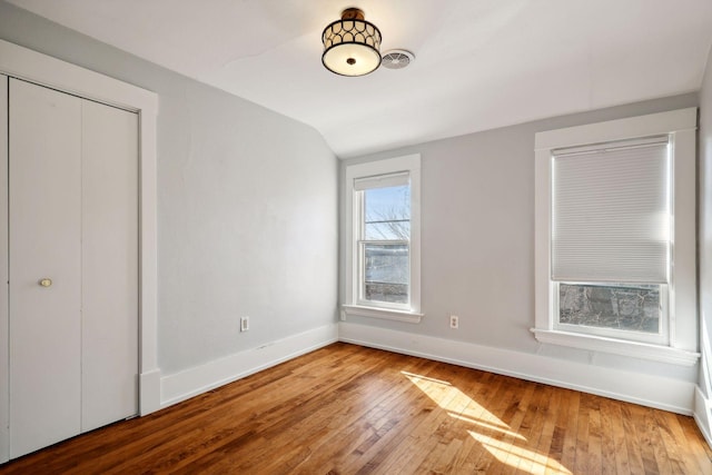 unfurnished bedroom with hardwood / wood-style floors, a closet, and vaulted ceiling