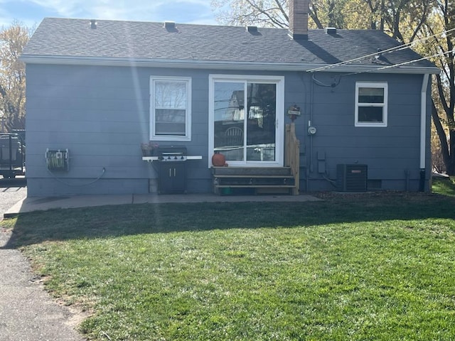 back of house with central air condition unit and a yard