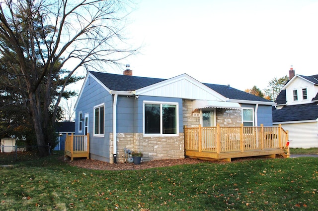 back of house featuring a lawn and a wooden deck