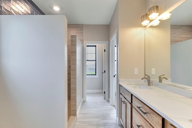 full bath with baseboards, wood finished floors, and vanity