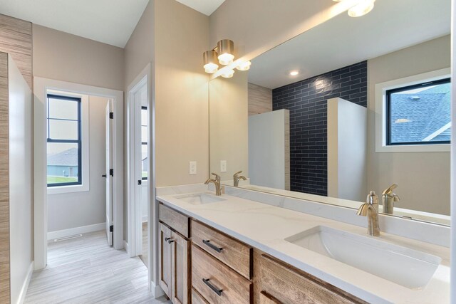 full bathroom featuring double vanity, wood finished floors, baseboards, and a sink