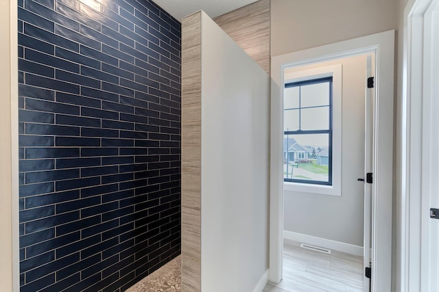 bathroom with baseboards, visible vents, and a tile shower