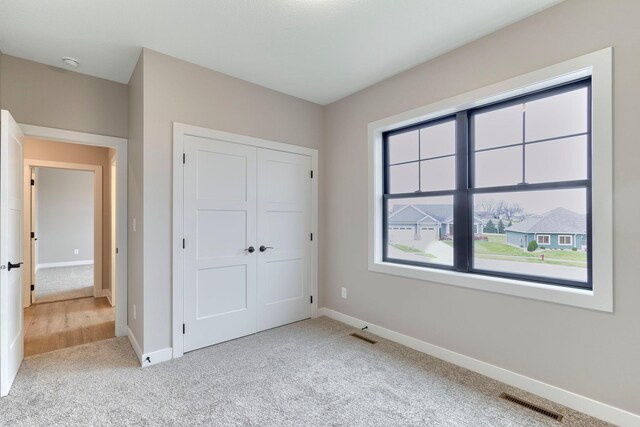 unfurnished bedroom with visible vents, baseboards, carpet, and a closet