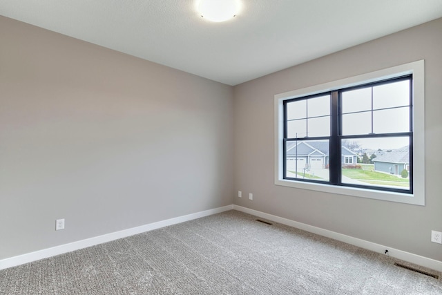 spare room with baseboards, visible vents, and light carpet