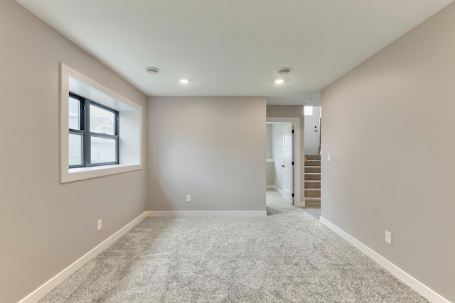 carpeted empty room featuring stairway, recessed lighting, and baseboards