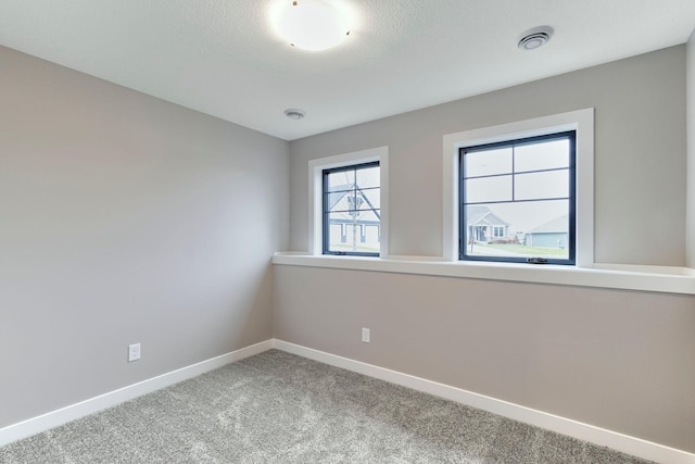 carpeted spare room with visible vents, baseboards, and a textured ceiling