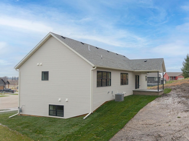 back of house featuring a lawn and a shingled roof