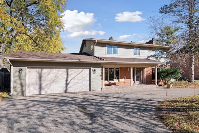 view of front facade featuring a garage, a chimney, covered porch, and driveway