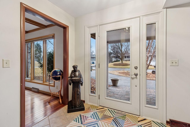 foyer entrance featuring light tile patterned floors, visible vents, and baseboards