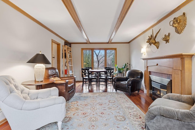 living area with a glass covered fireplace, crown molding, beamed ceiling, and wood finished floors