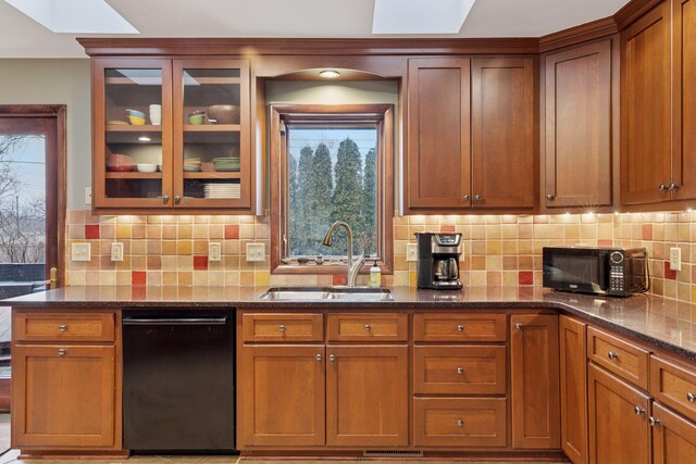 kitchen with dark stone countertops, a sink, black appliances, glass insert cabinets, and backsplash