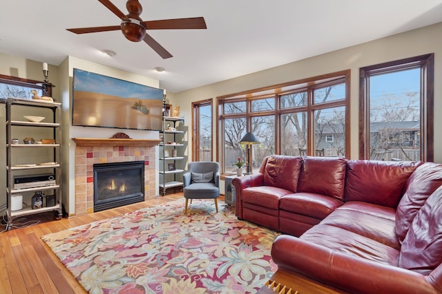 living area with vaulted ceiling, plenty of natural light, wood finished floors, and a tile fireplace