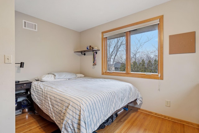 bedroom with visible vents, baseboards, and wood finished floors