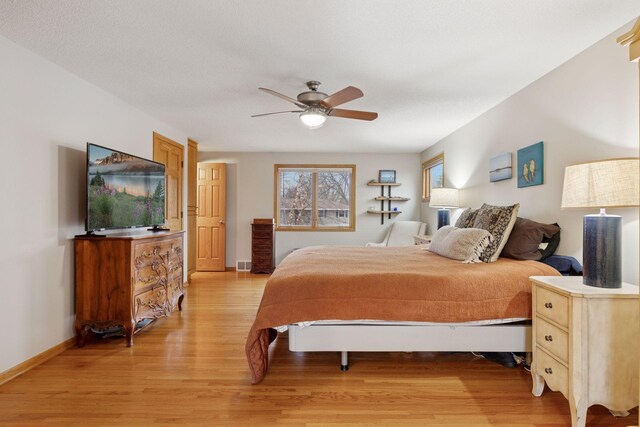 bedroom with visible vents, light wood-style floors, baseboards, and ceiling fan