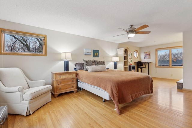 bedroom featuring ceiling fan, a textured ceiling, and light wood-style floors