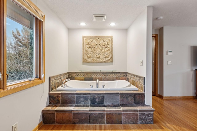 bathroom featuring a bath, a textured ceiling, and wood finished floors