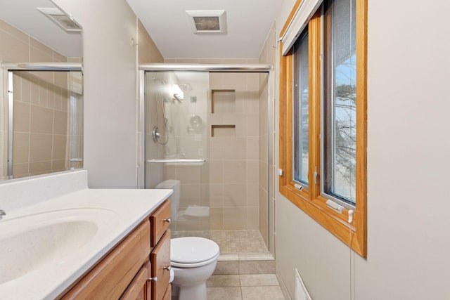 bathroom with vanity, a shower stall, toilet, and visible vents