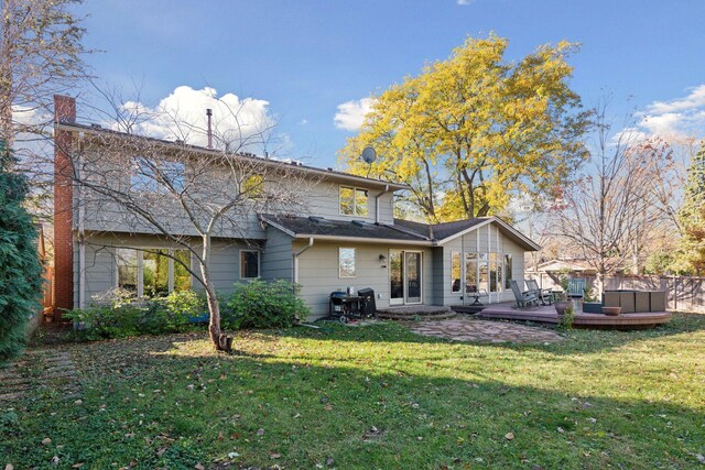 back of property with a yard, a deck, and a chimney