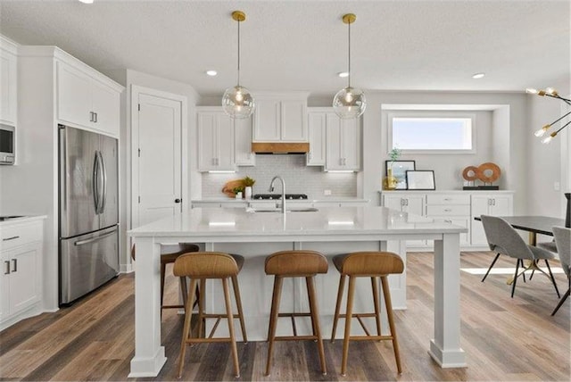 kitchen with dark hardwood / wood-style flooring, white cabinets, appliances with stainless steel finishes, and hanging light fixtures