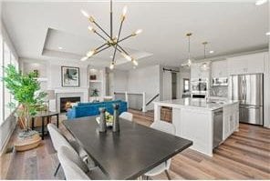 dining space with light wood-type flooring, a chandelier, and a tray ceiling