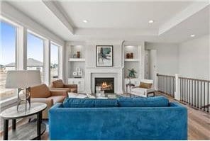 living room with built in features, a tray ceiling, and hardwood / wood-style flooring