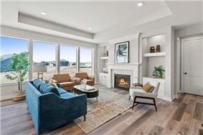 living room with built in shelves, hardwood / wood-style flooring, and a raised ceiling