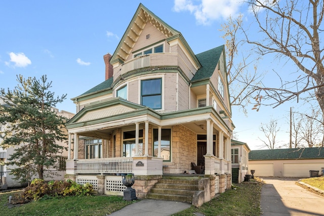 victorian house featuring a porch and a garage