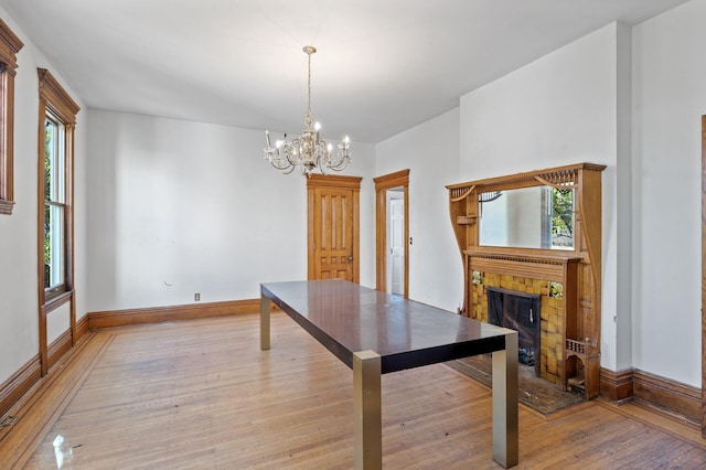 dining space featuring a tile fireplace, plenty of natural light, and light hardwood / wood-style flooring