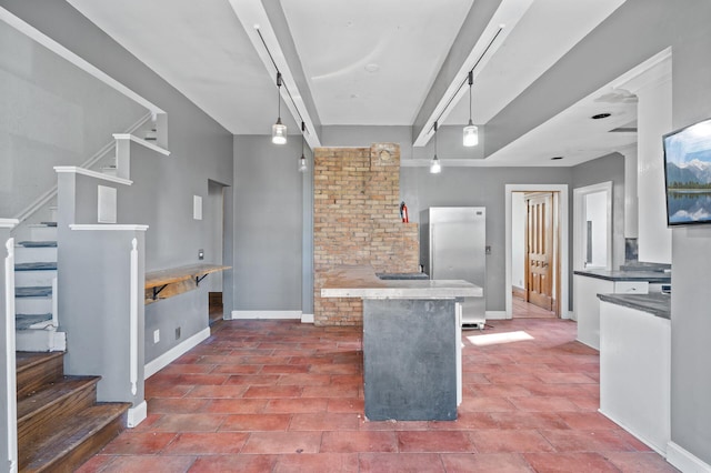 kitchen featuring white cabinets, hanging light fixtures, and stainless steel refrigerator