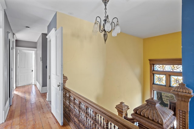 corridor with light hardwood / wood-style floors and an inviting chandelier