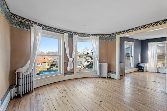 spare room with radiator heating unit and wood-type flooring