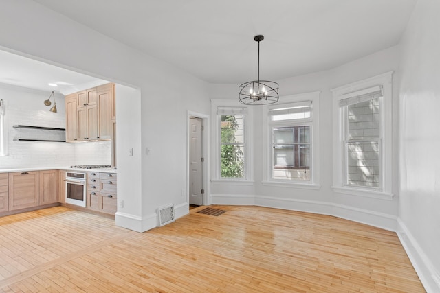 unfurnished dining area with a notable chandelier and light hardwood / wood-style floors