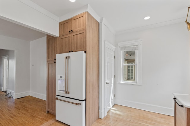 kitchen with light brown cabinets, light hardwood / wood-style floors, crown molding, and high end white fridge