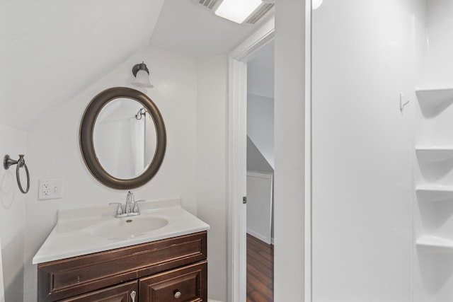 bathroom with wood-type flooring, vanity, and lofted ceiling