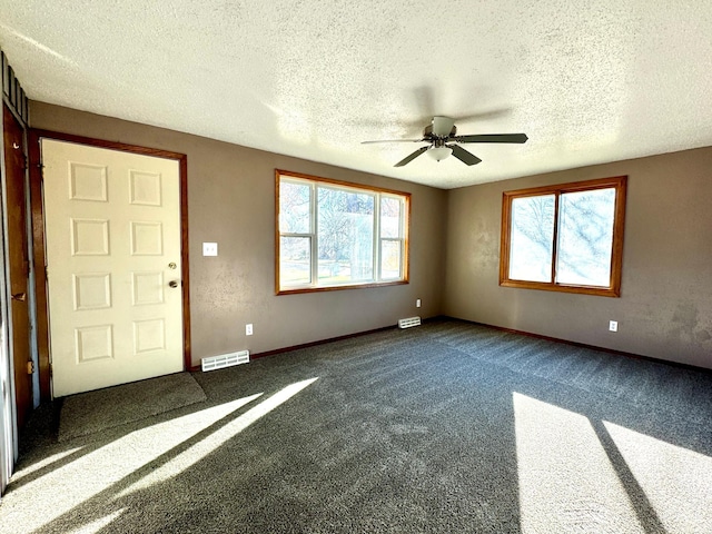 unfurnished living room with a textured ceiling, ceiling fan, and dark carpet