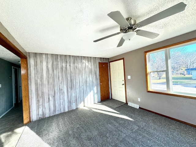 empty room featuring a textured ceiling, carpet floors, and ceiling fan