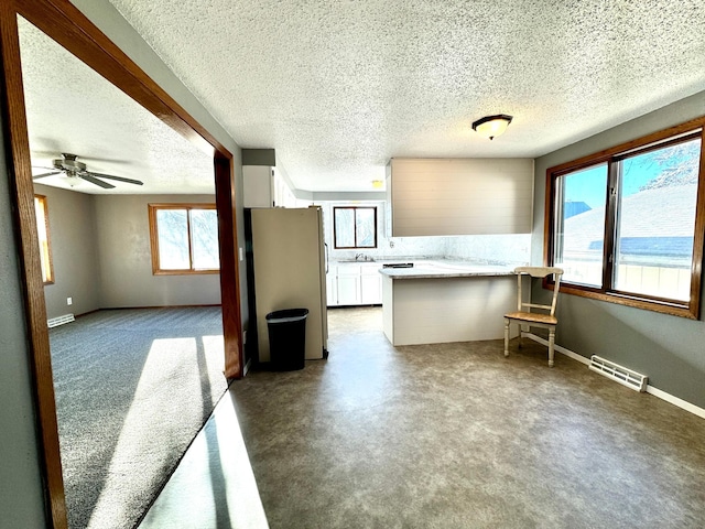 kitchen with white cabinetry, plenty of natural light, a textured ceiling, and white refrigerator