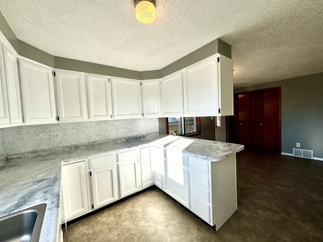 kitchen featuring kitchen peninsula, a textured ceiling, and white cabinets