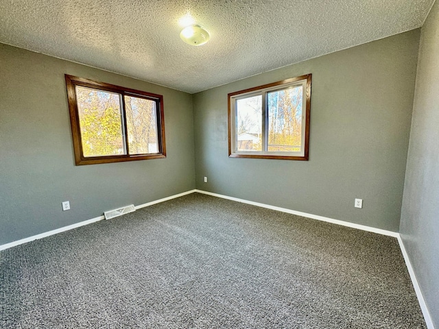 carpeted empty room featuring a textured ceiling