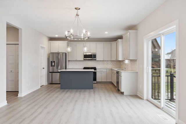 10191 Arrowwood Path, Woodbury, MN 55129 - kitchen with appliances with stainless steel finishes, a chandelier, light wood-style floors, decorative backsplash, and light countertops