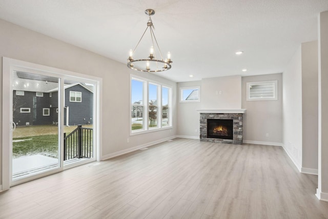 unfurnished living room with a chandelier, a fireplace, and light wood-type flooring