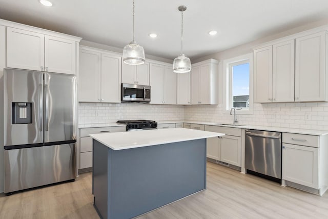 kitchen with a kitchen island, decorative light fixtures, sink, white cabinets, and stainless steel appliances