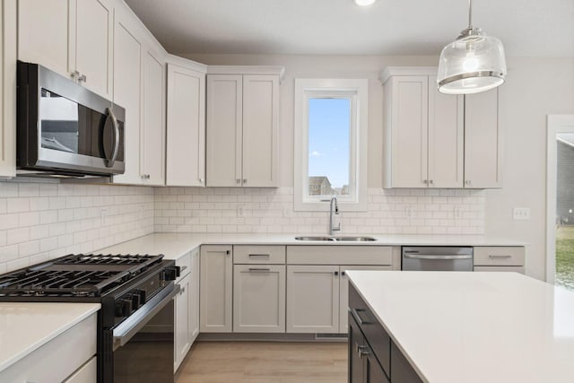 kitchen featuring sink, decorative light fixtures, stainless steel appliances, and white cabinets