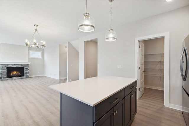 kitchen featuring hanging light fixtures, a stone fireplace, a center island, and light hardwood / wood-style floors