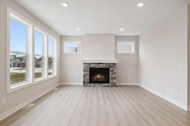 unfurnished living room featuring a stone fireplace and light hardwood / wood-style floors