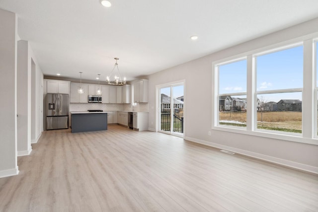 unfurnished living room featuring an inviting chandelier and light hardwood / wood-style floors