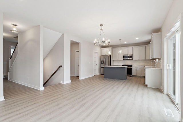 kitchen featuring sink, gray cabinetry, stainless steel appliances, a kitchen island, and decorative light fixtures