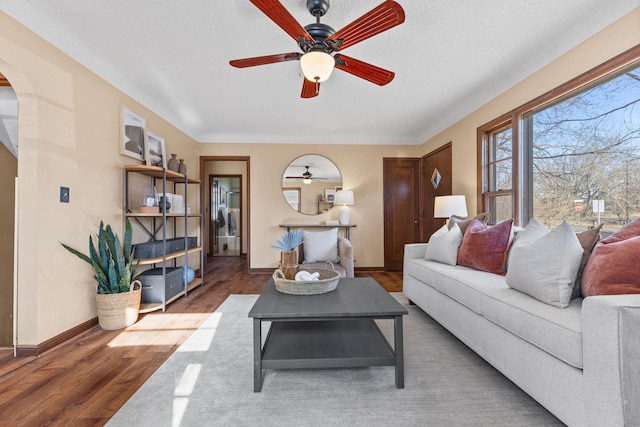 living room featuring ceiling fan, dark hardwood / wood-style floors, and a textured ceiling