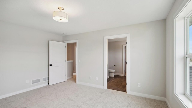 unfurnished bedroom with ensuite bathroom and light colored carpet